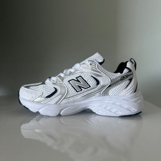 Zapatillas premium modelo 530 blanca con detalles gris y negros.